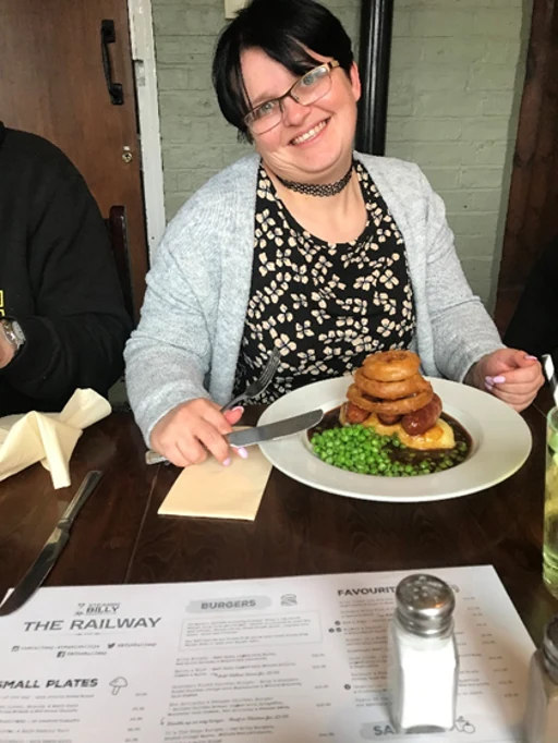 A woman sitting with a meal and a drink