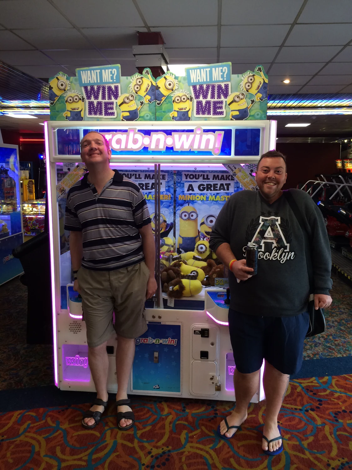 Two men posing beside an arcade machine
