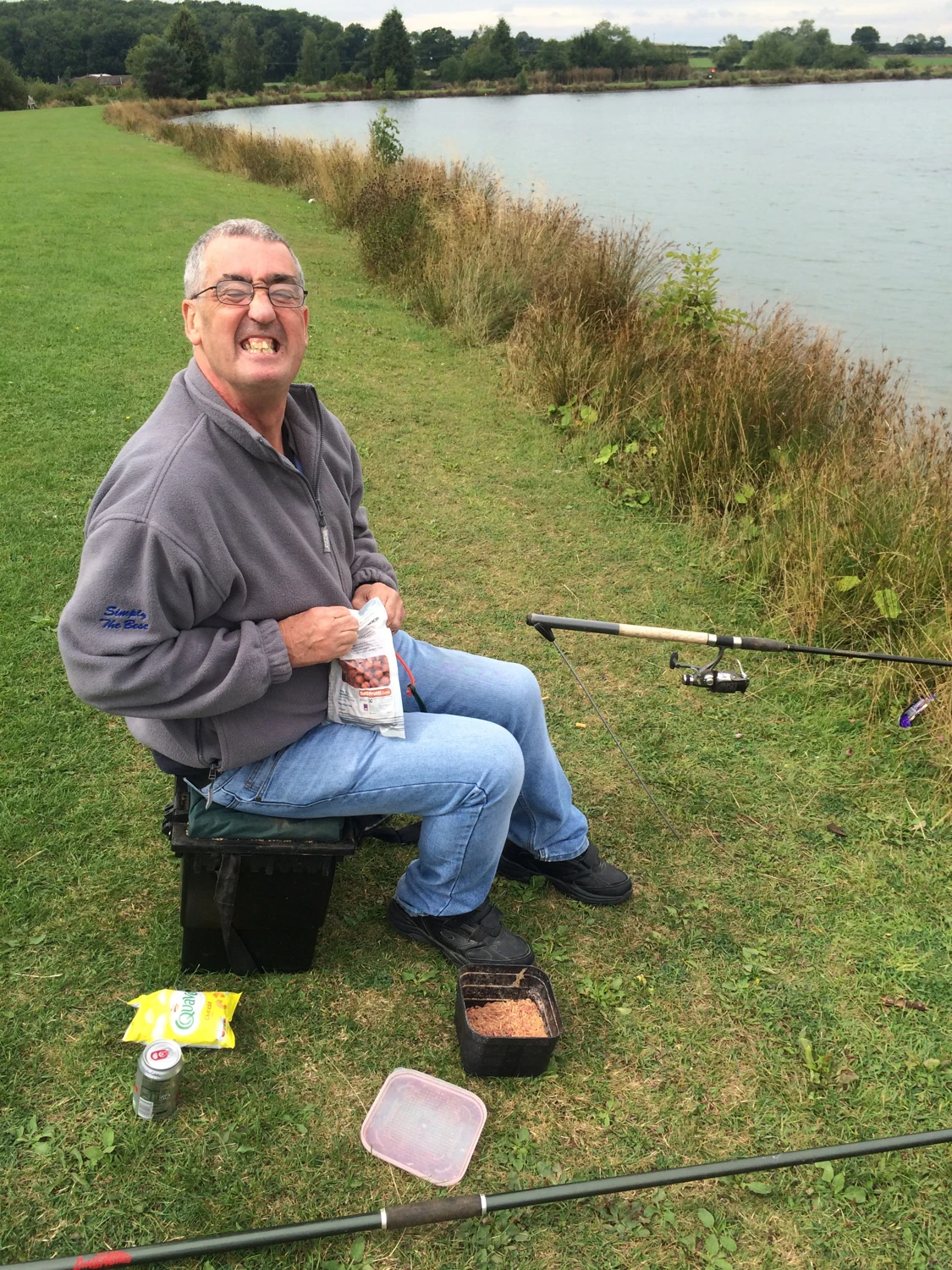 A man seated beside a lake on a fishing trip