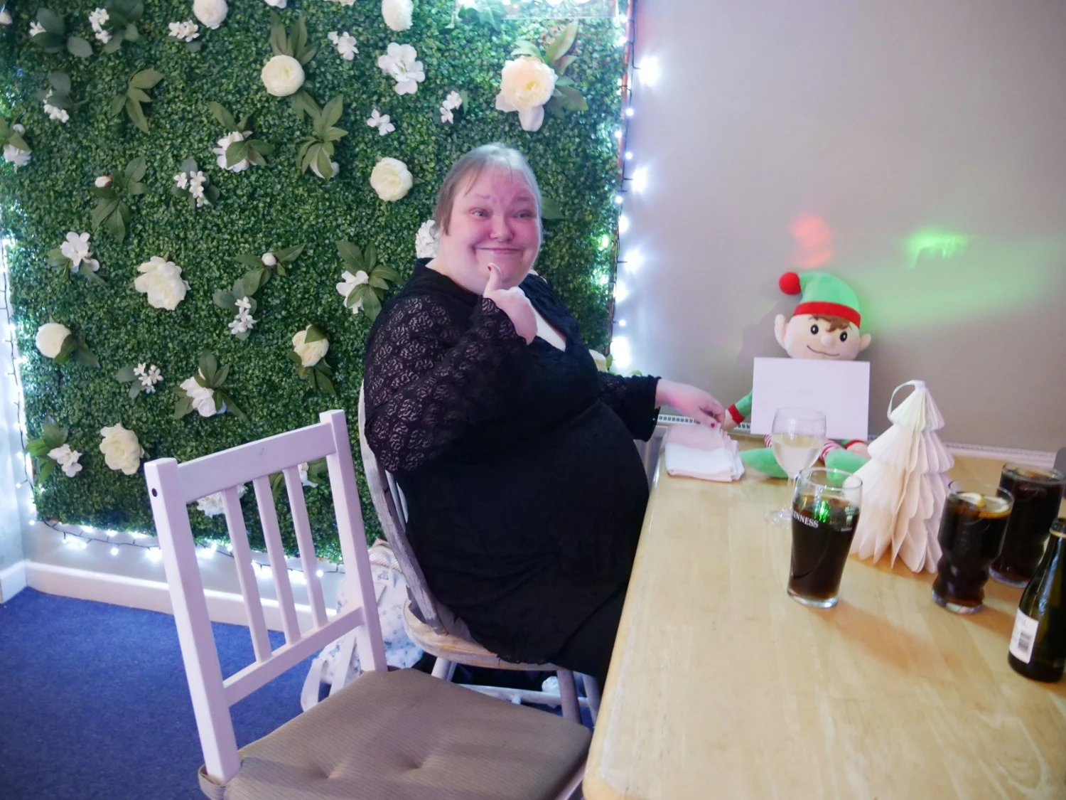 A woman seated beside a decorated Christmas tree