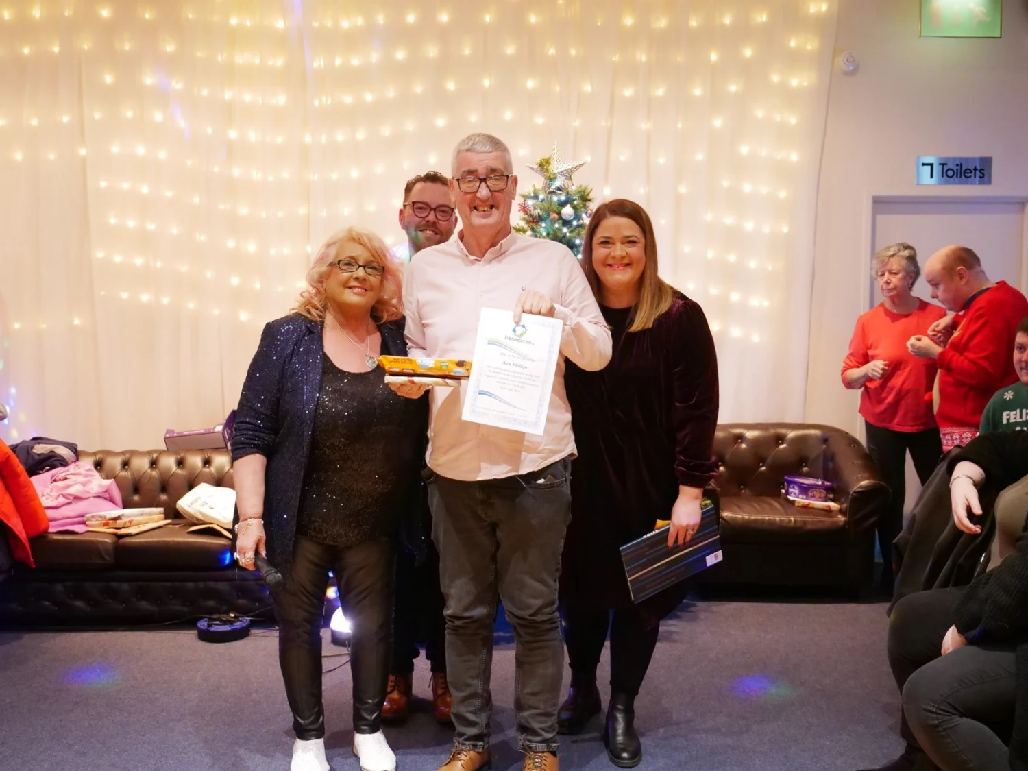 An awards recipient in a white shirt holding a certificate