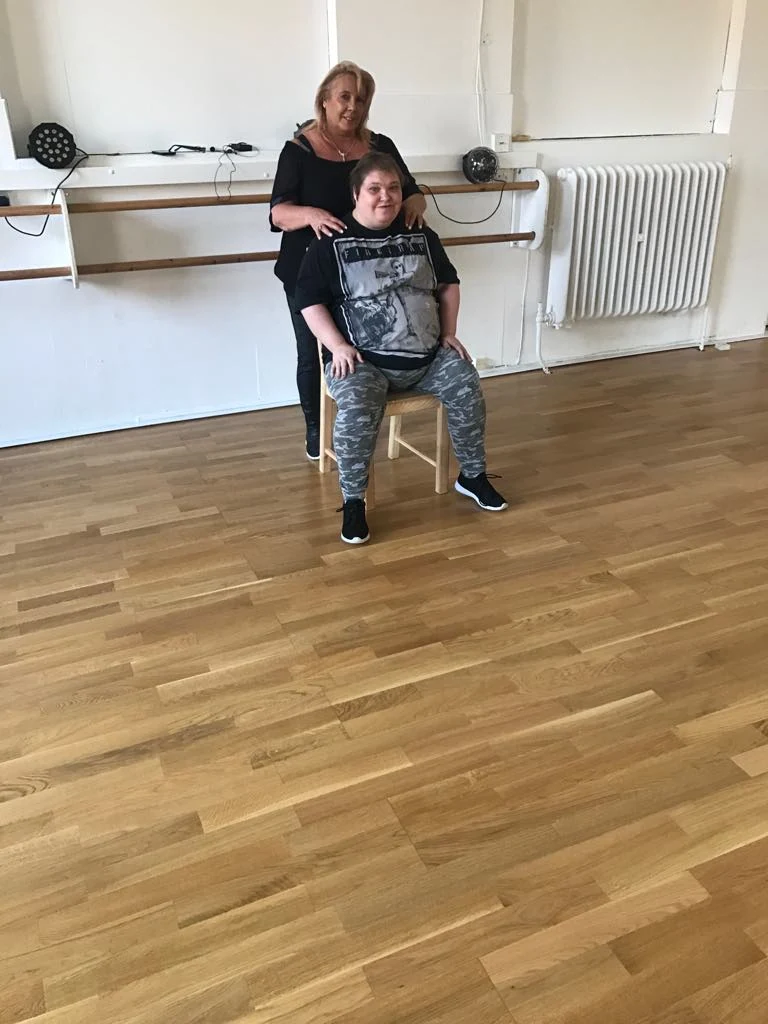 A seated participant with a supporter in an activity room