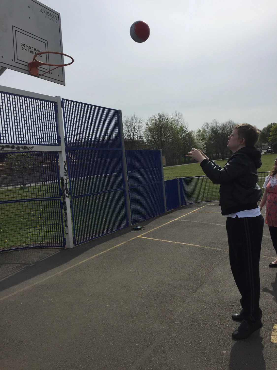 A person shooting at an outdoor basketball hoop