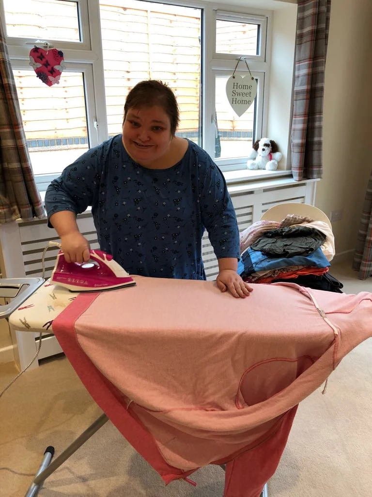 A woman ironing a pink garment