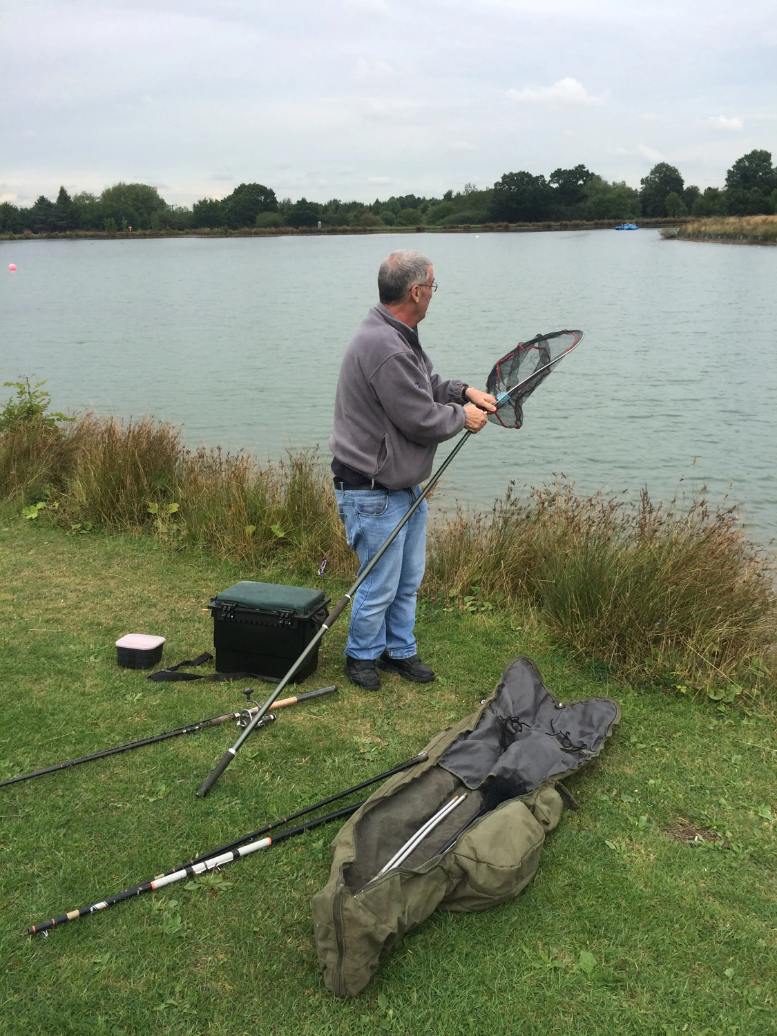 A man holding a fishing net beside a lake