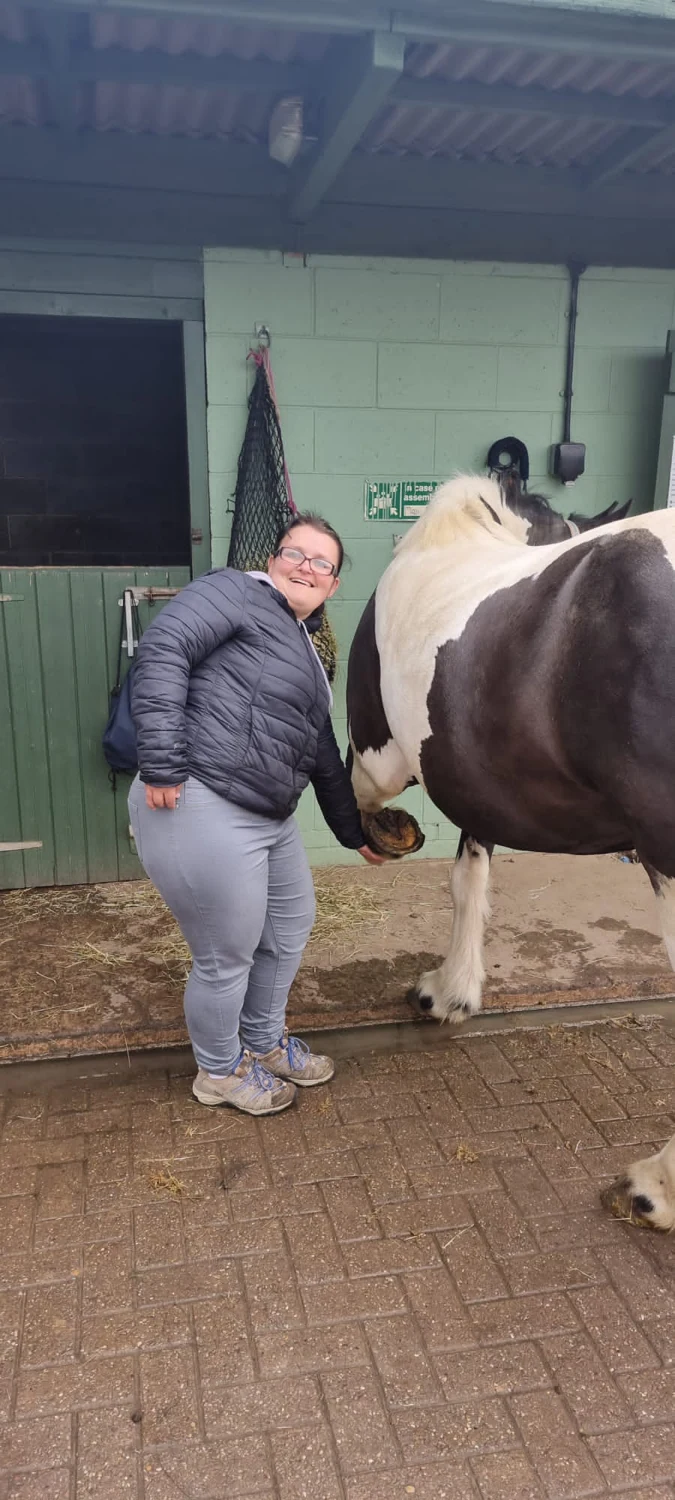 A person visiting a horse in a stable