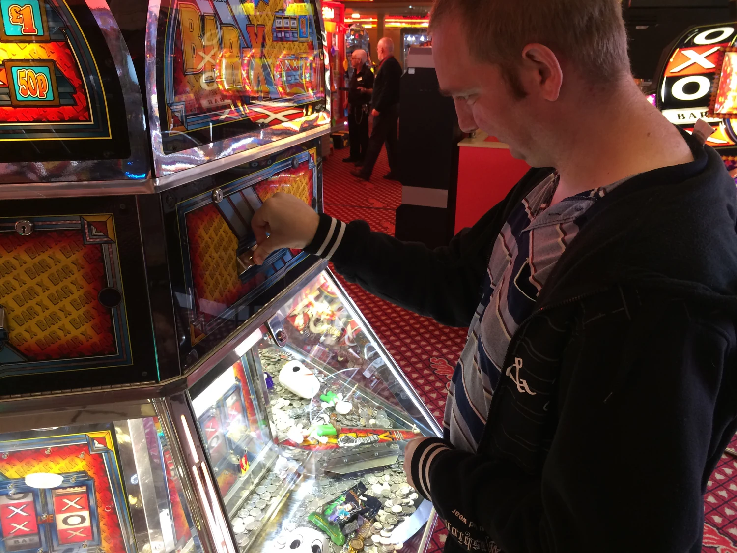 A man using a coin-pusher arcade machine