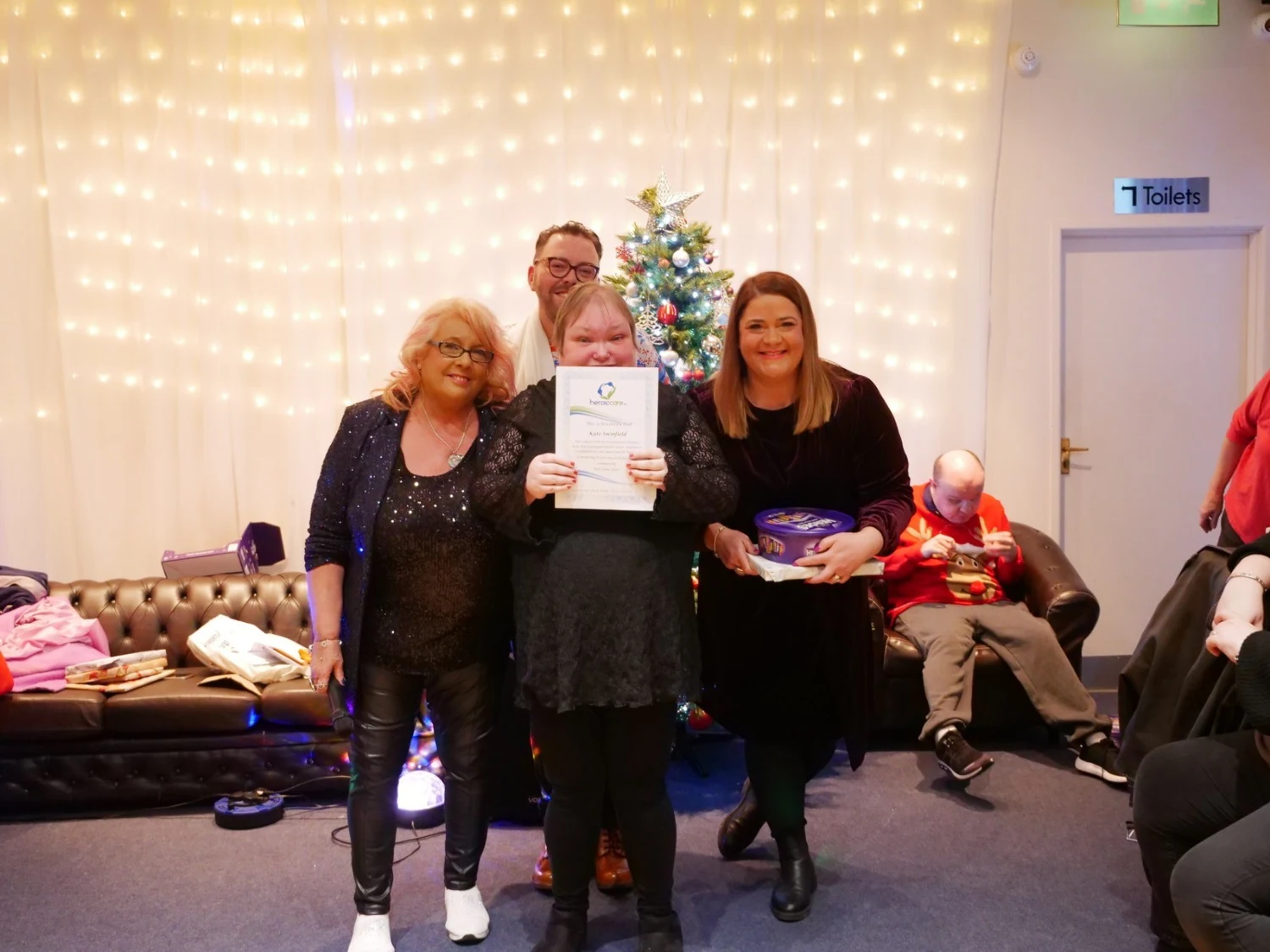 An awards recipient holding a certificate with two supporters