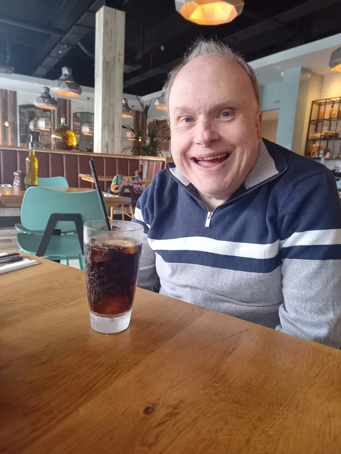A man smiling over a drink in a cafe