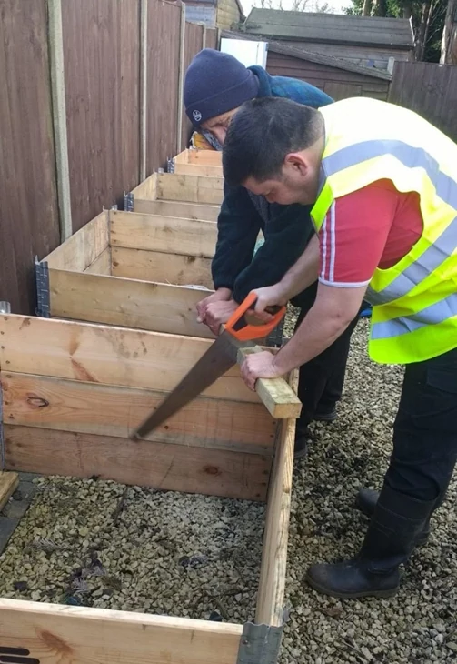 A man sawing timber for a garden project