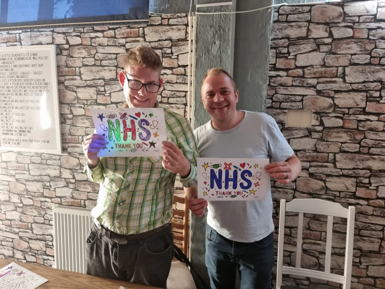 Two men holding handmade NHS thank-you signs