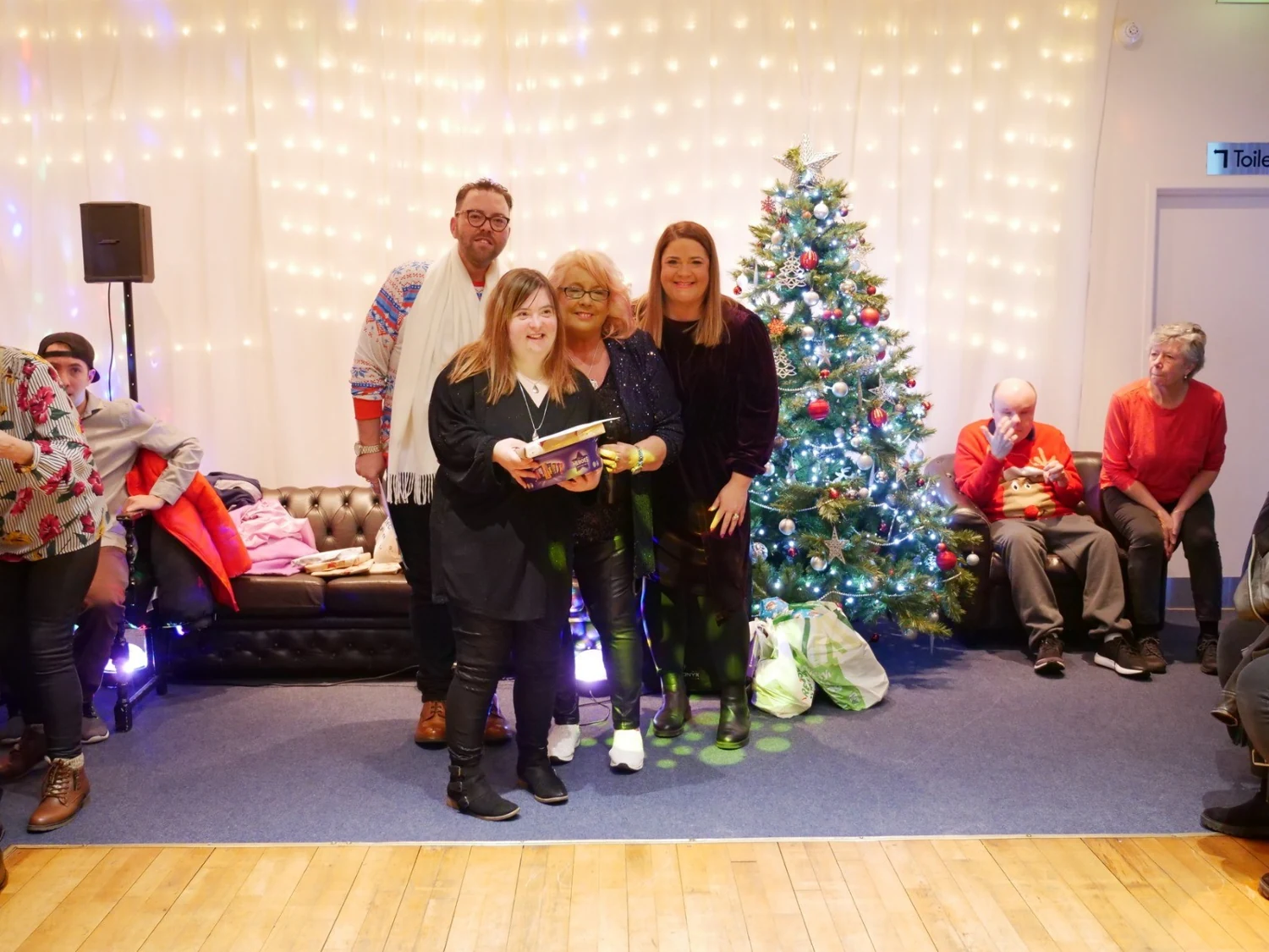 An awards recipient holding a gift with two supporters