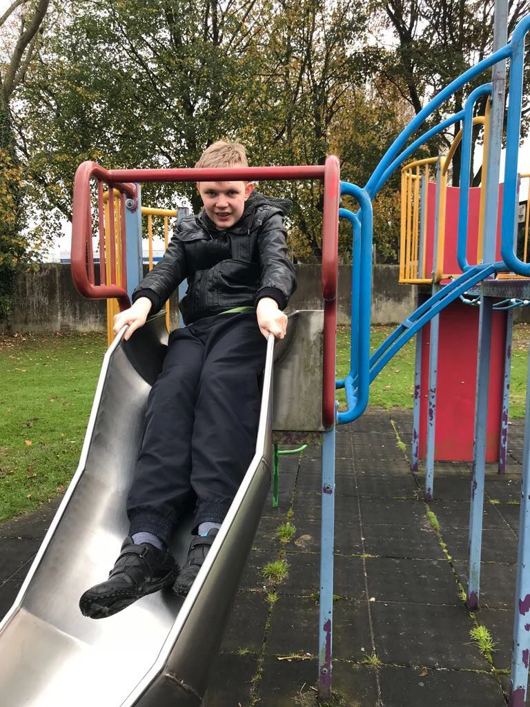 A man sitting at the bottom of a playground slide