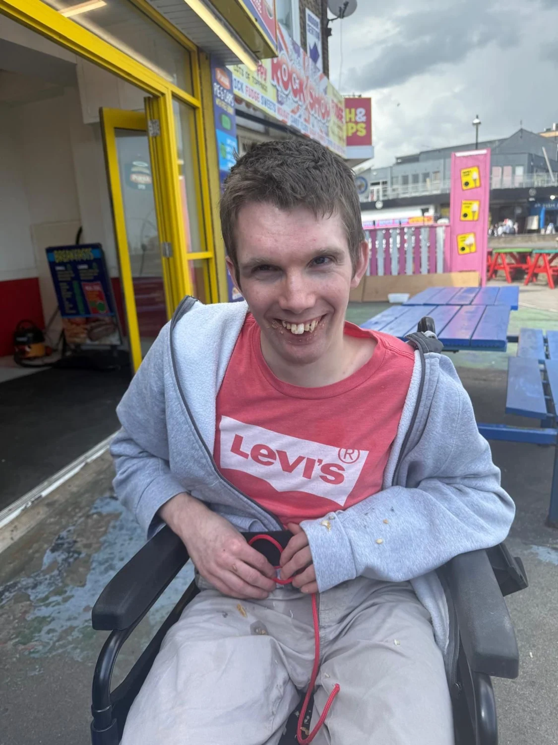 A man smiling outside a seaside shop