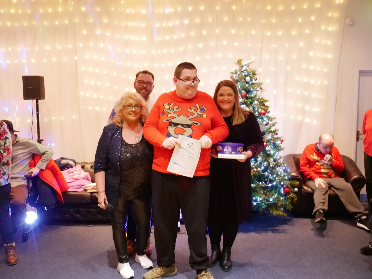An awards recipient in a red top holding a gift and certificate