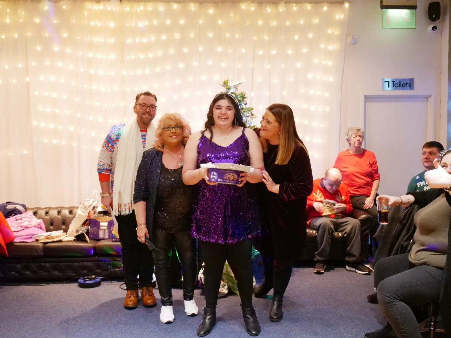 An awards recipient in a purple top with two supporters