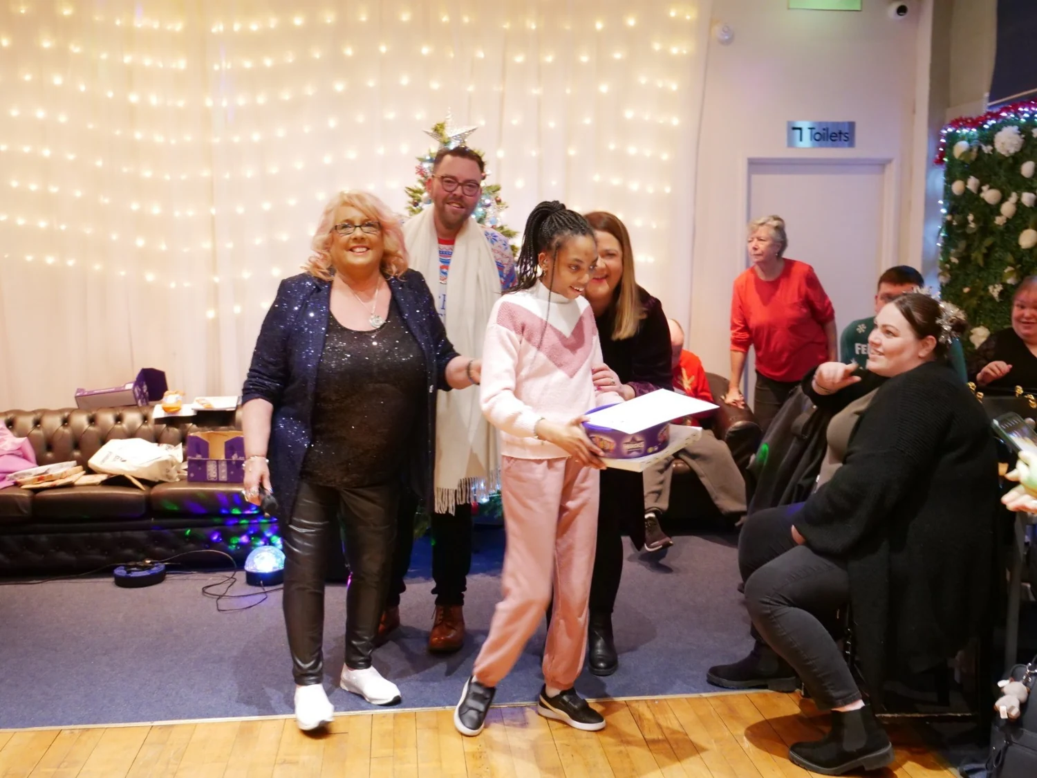 An awards recipient in a pink outfit holding a certificate