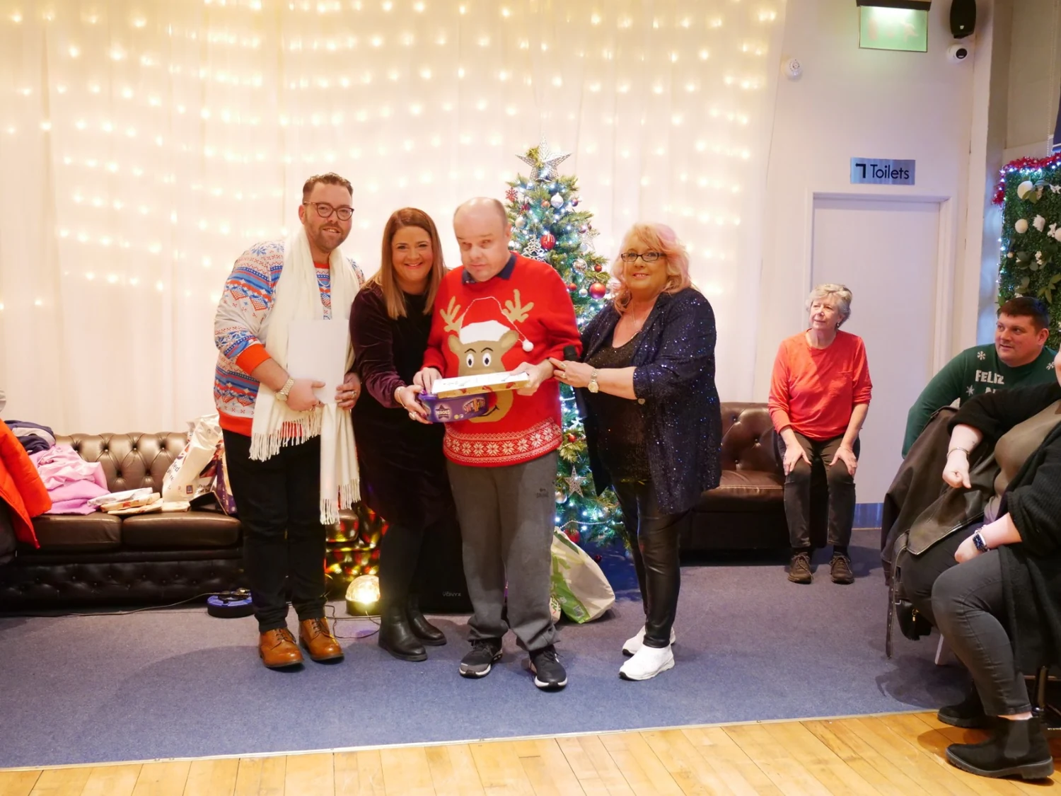 An awards recipient in a festive jumper with supporters